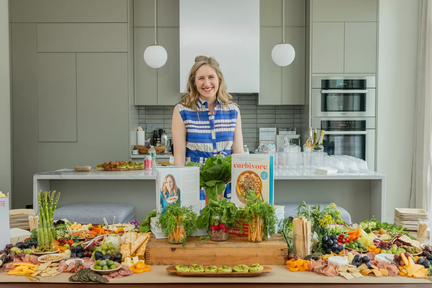 Author standing behind a colorful food and book display