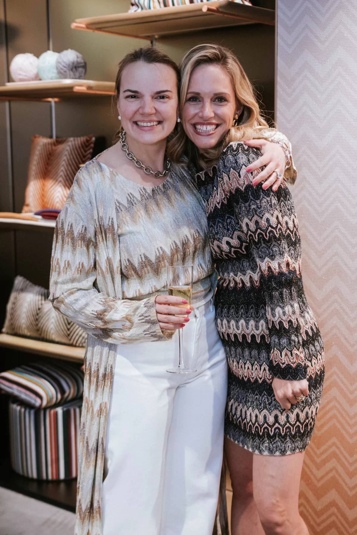 Two guests embracing at a fashion shopping event
