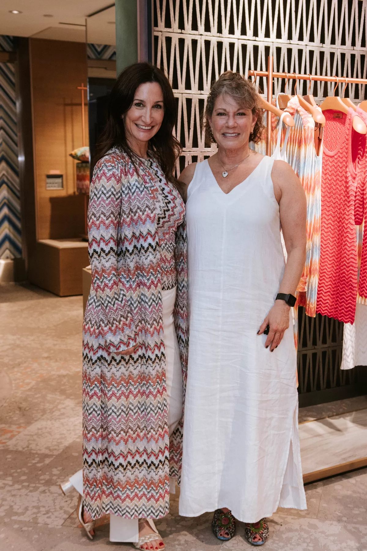 Two attendees posing together in a fashion showroom