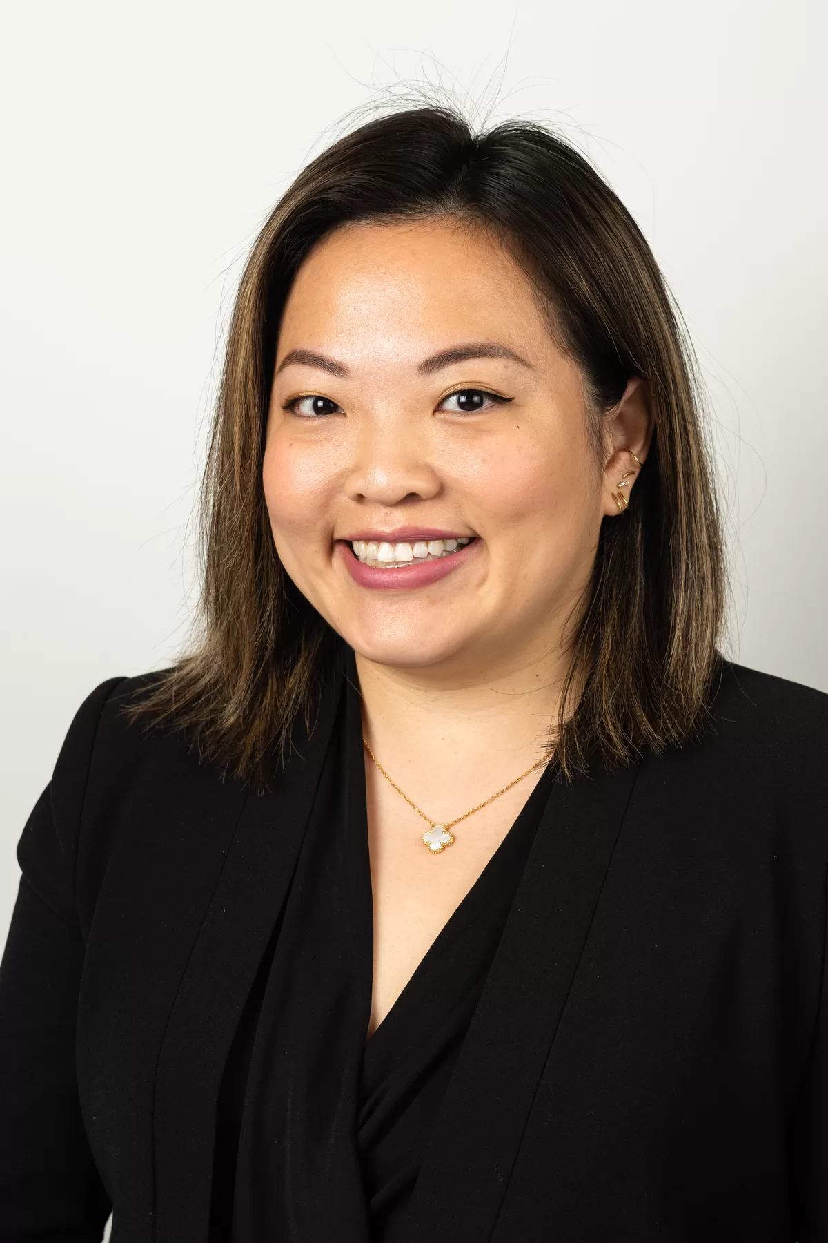 Professional female headshot in a black blazer on a light background