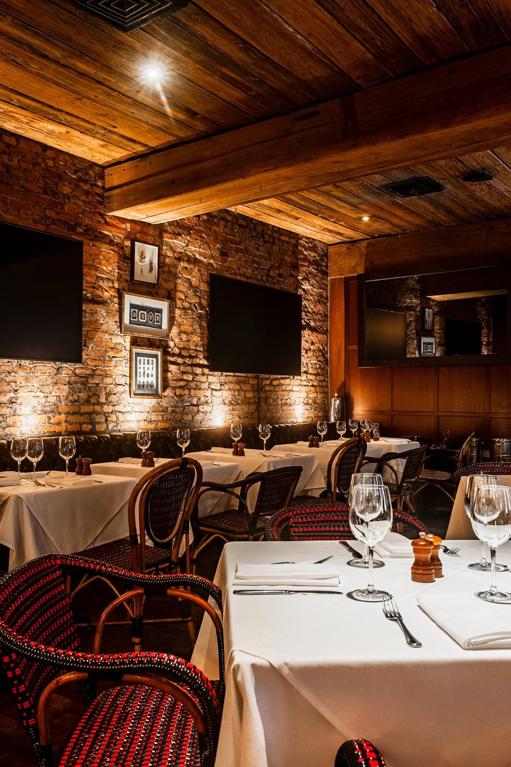 PJ Clarke's dining room in New York City with exposed brick, a reclaimed wood ceiling and set tables