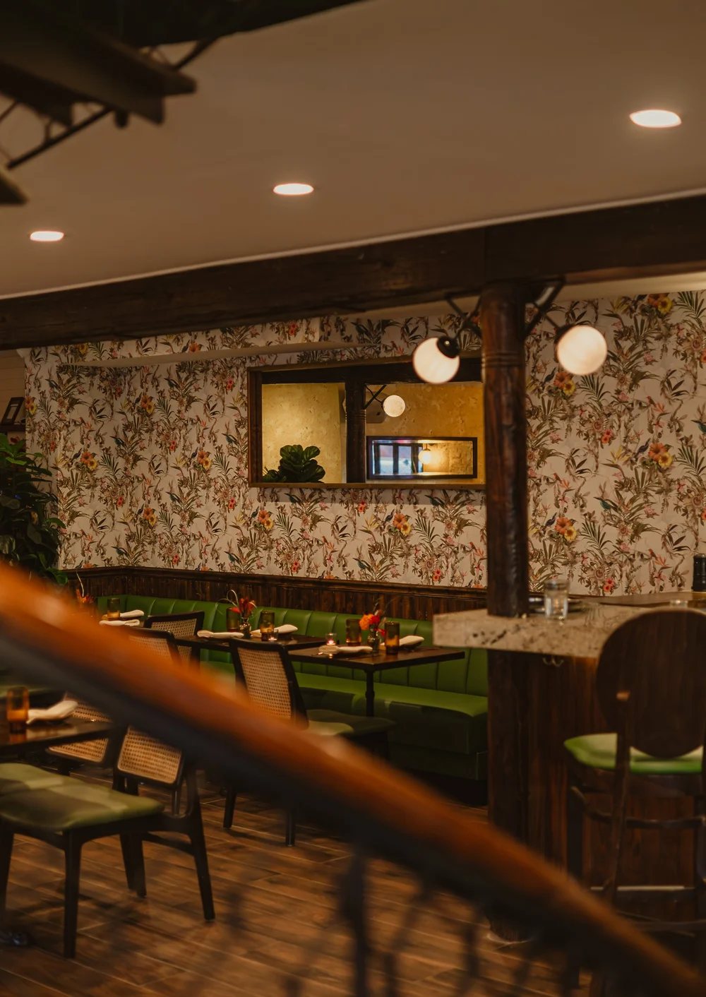 Mango Bay dining room with botanical wallpaper, green banquettes and a terrazzo bar