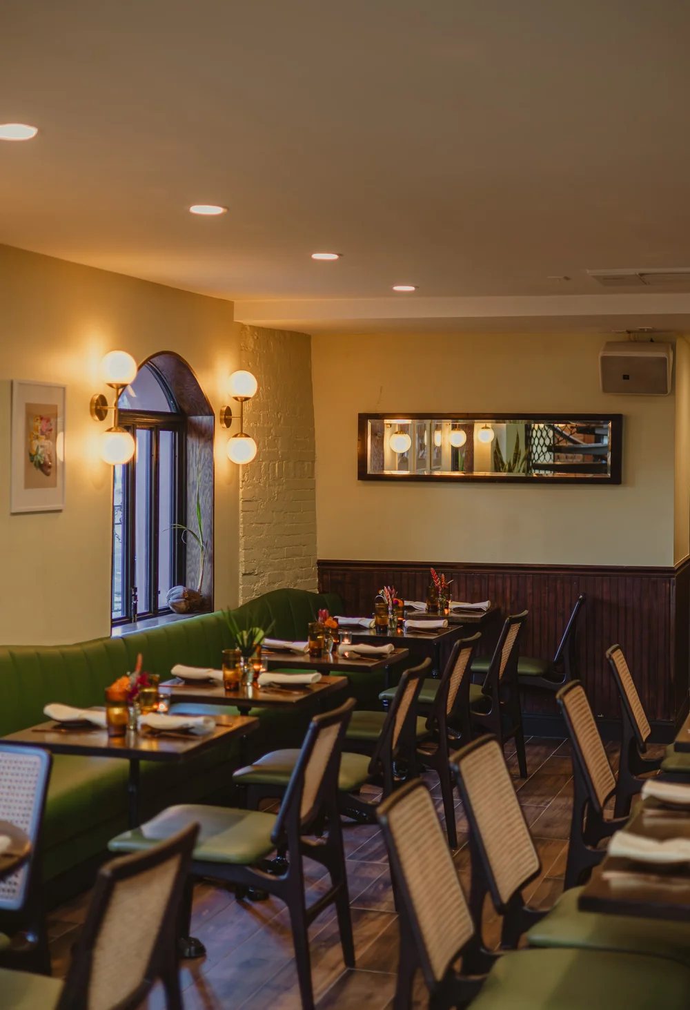 Mango Bay banquette seating and arched window with globe sconces in a New York restaurant